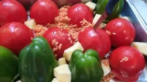 Farcir tomates et poivrons avec la préparation Remettre les couvercles sur les légumes Dans un plat allant au four, placer les légumes sur leur couvercle (couvercle en bas)